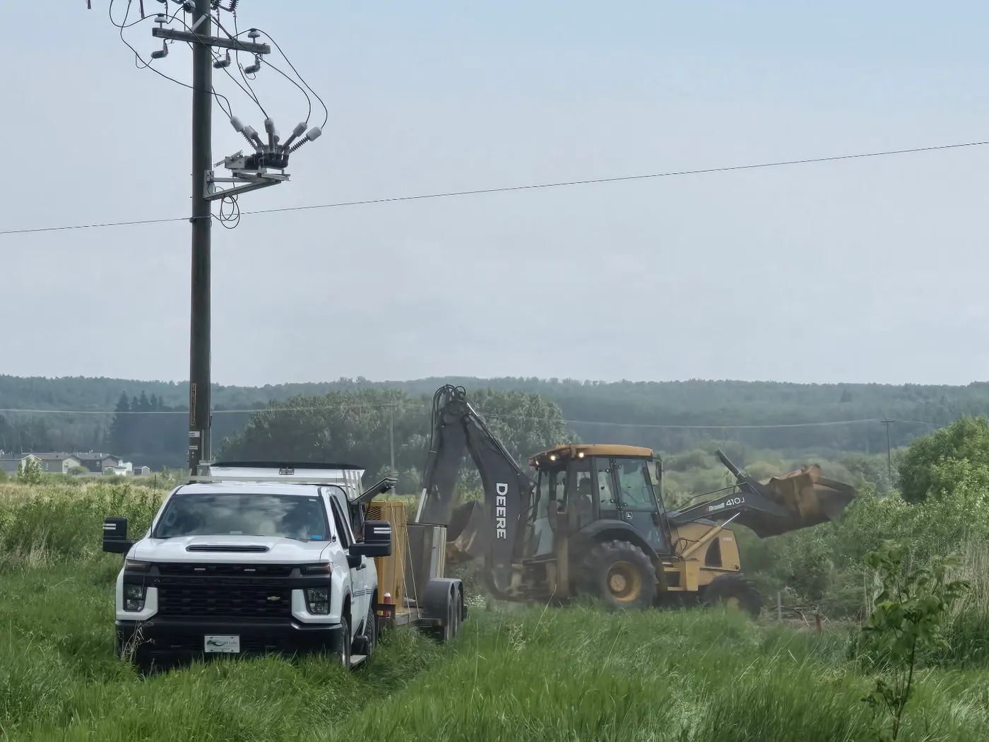 Excavator and service truck on a rural acreage sewer job
