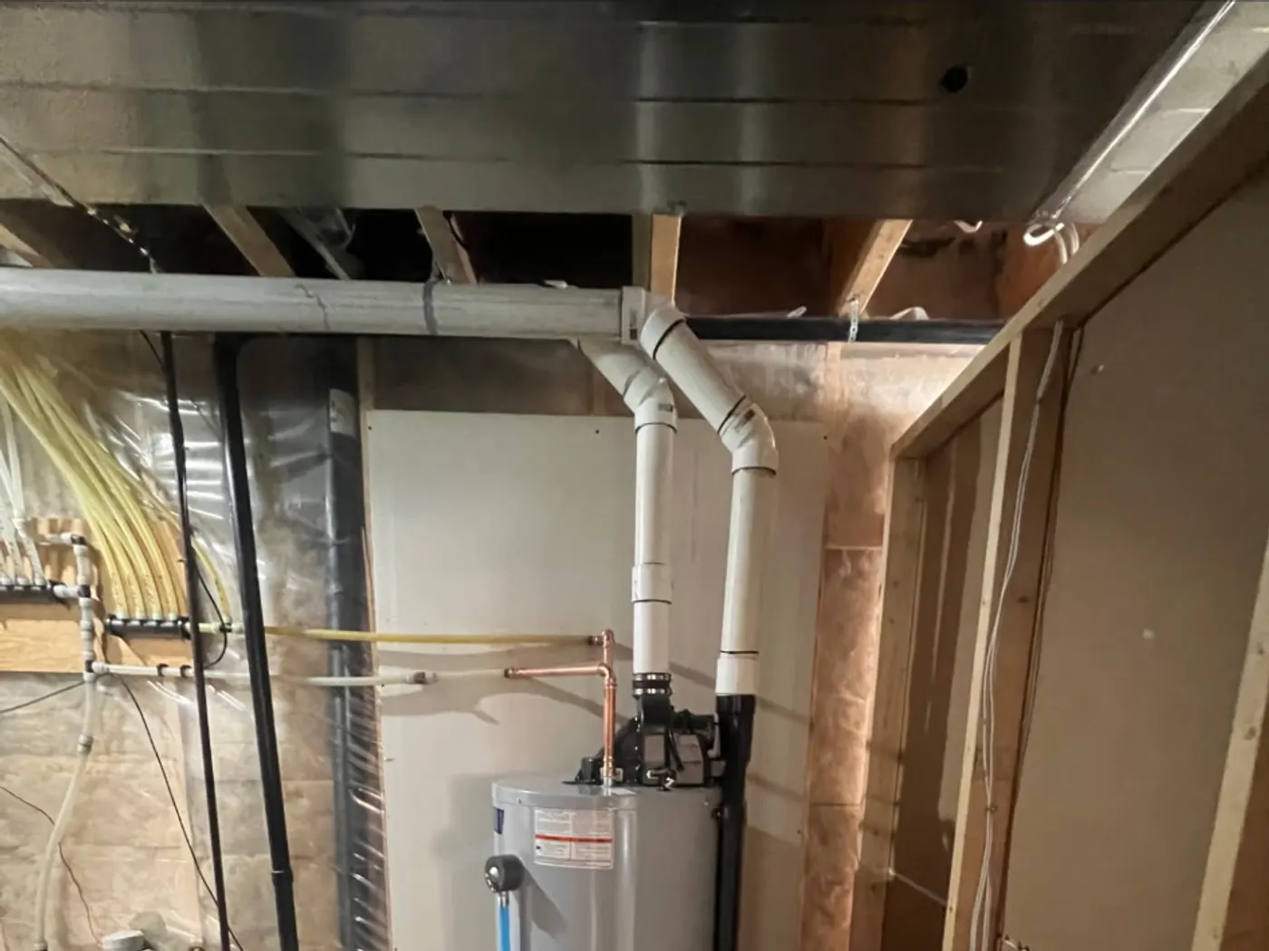 Technician strapping in a new hot water tank next to the old unit marked for haul-away