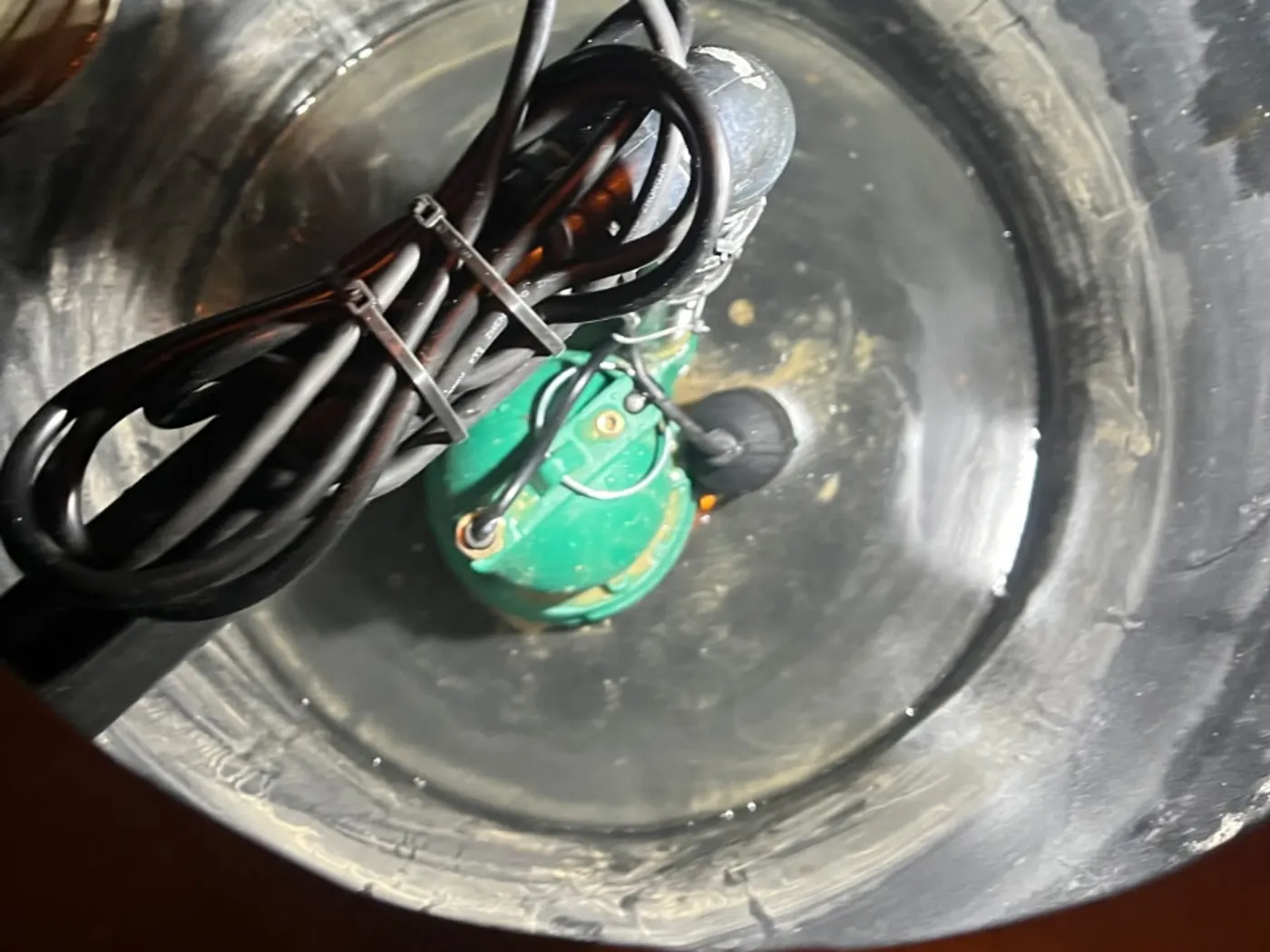 Technician testing a sump pump in a basement pit