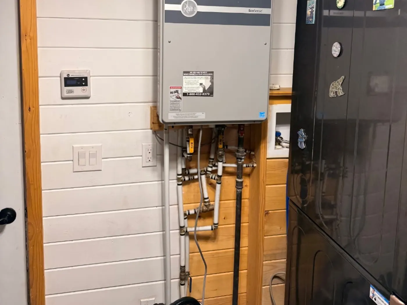 Technician adjusting the gas valve on a wall-mounted tankless water heater